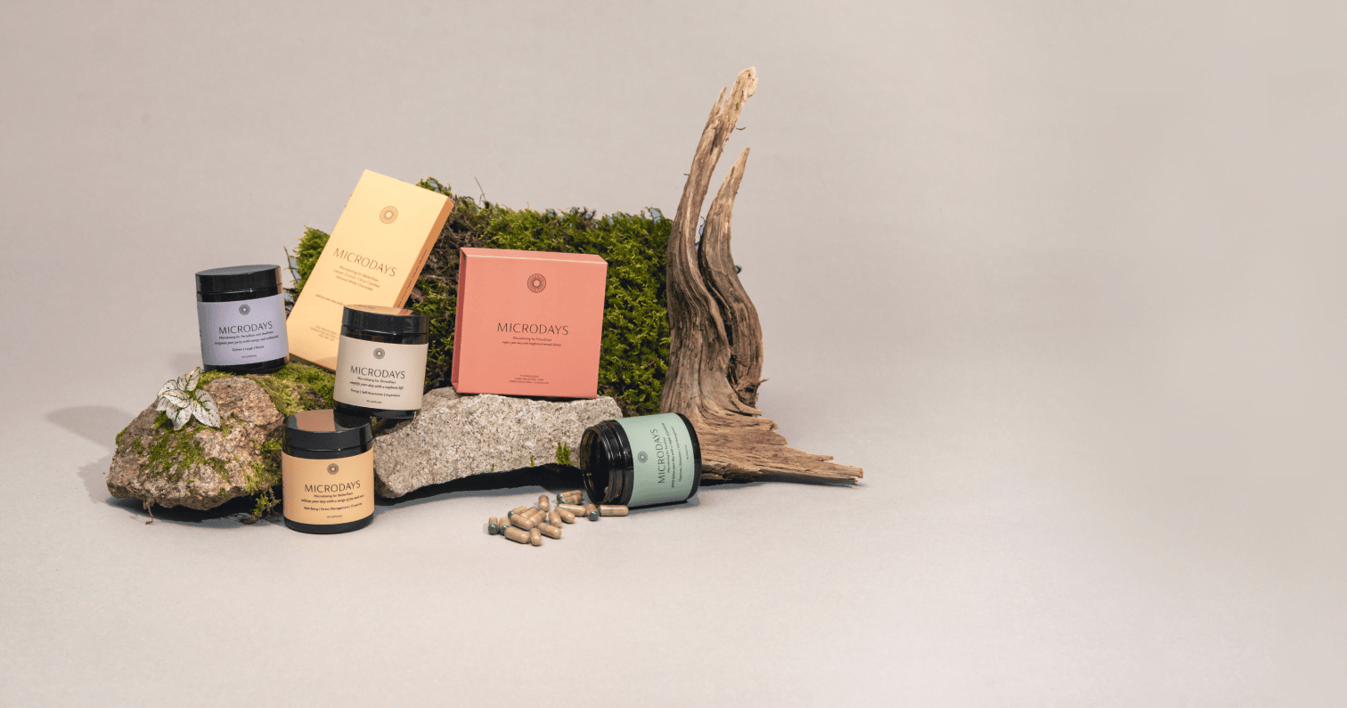 MicroDays microdose capsule jars and chocolate boxes styled on moss, rocks and driftwood