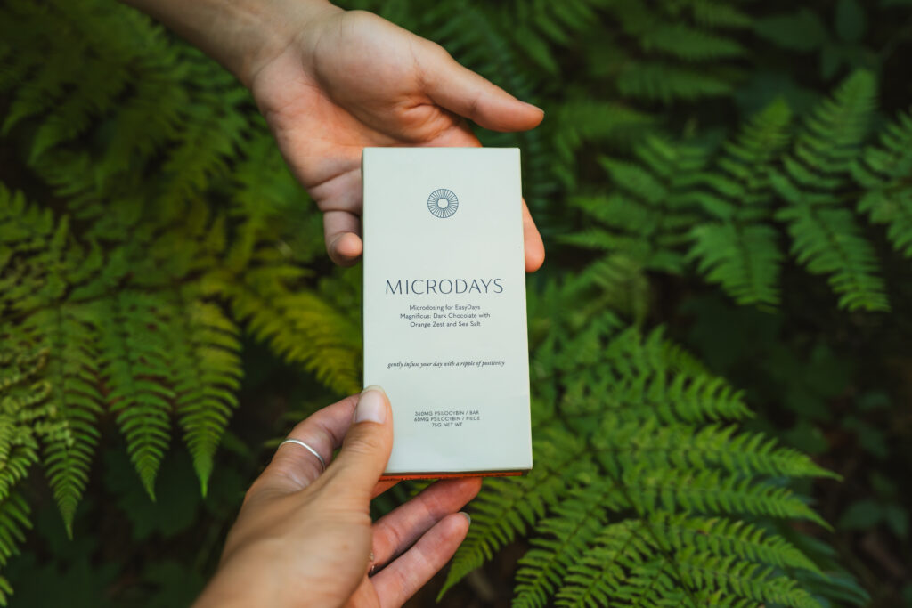 Hands holding a MicroDays chocolate bar among green ferns